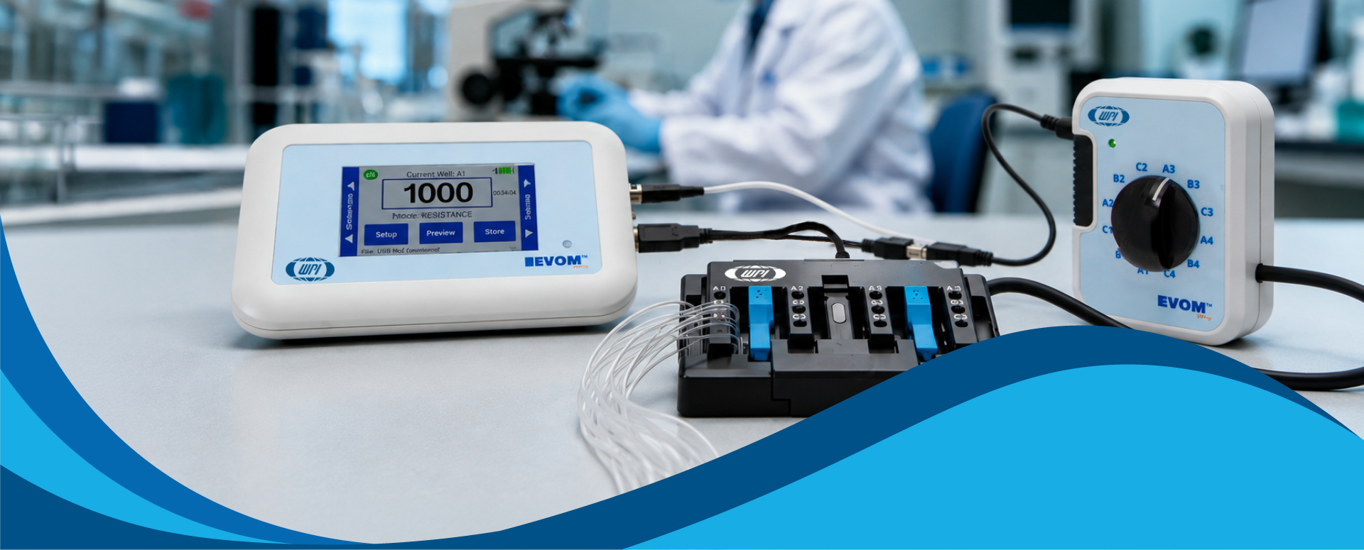 EVOM electronic device kit with a white digital controller, a white dial unit, and a black multi-socket connector block on a white table, with a blurred lab background and a blue graphic wave at the bottom.